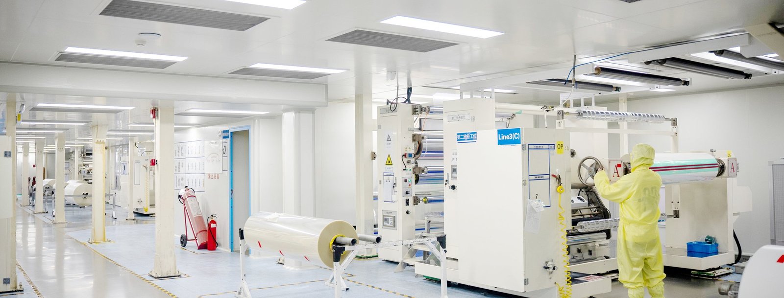 Precision coating line inside the Class 100 cleanroom, with an operator in a cleanroom suit