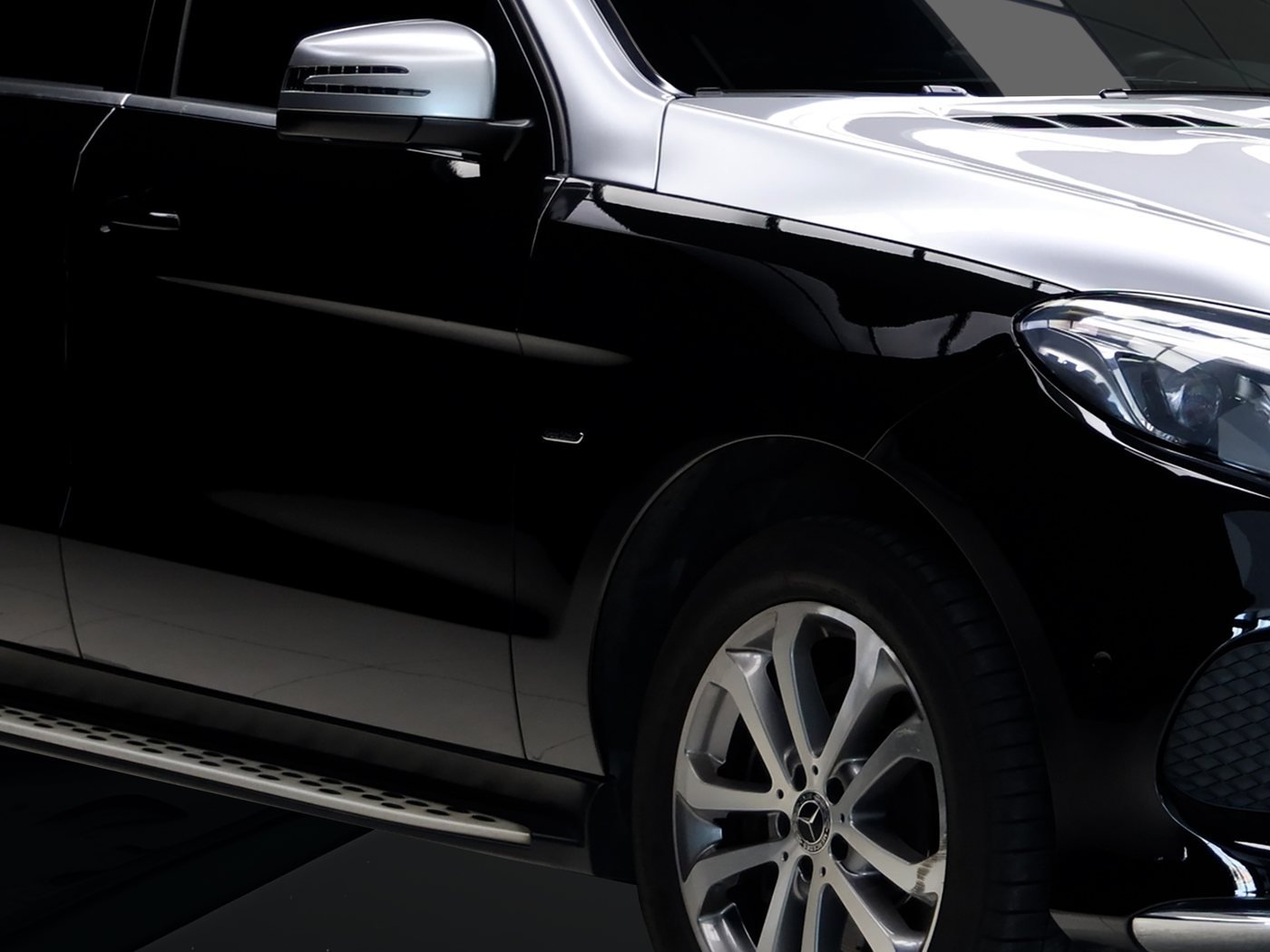 Gloss black door and front wing of an SUV, the kind of dark paint where swirl marks show most