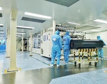 Operators in cleanroom suits at a precision coating line