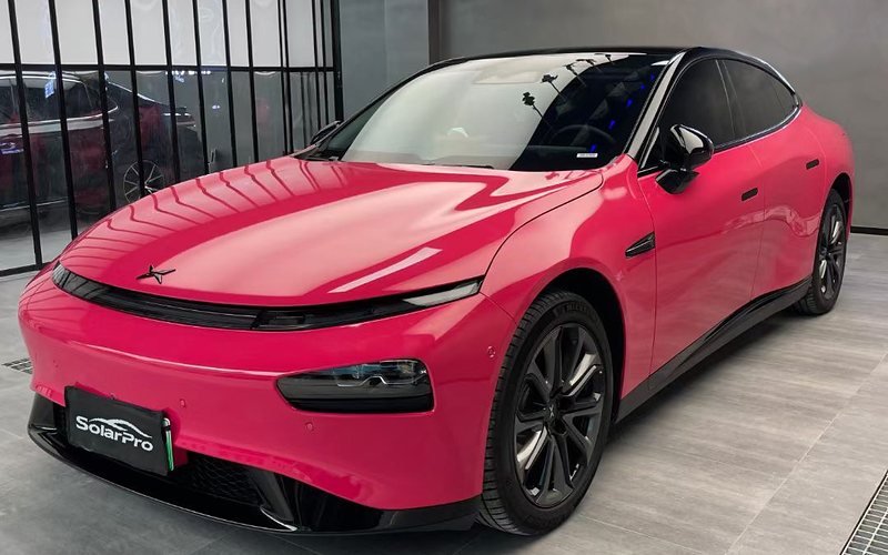 Hot-pink electric saloon in an install bay, fitted with a SolarPro plate