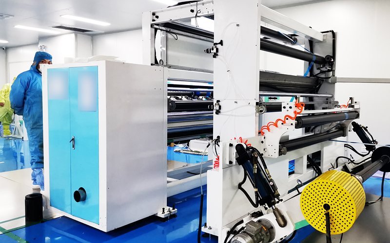 Operator in a cleanroom suit beside a film converting machine in our Jiangsu plant