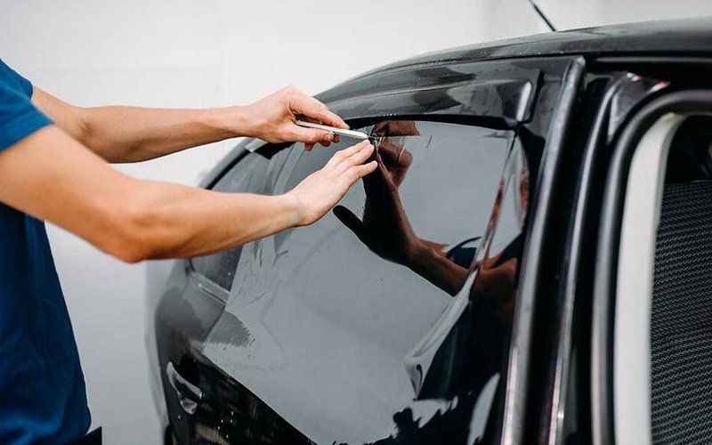 Installer pressing window film onto the glass of an open car door